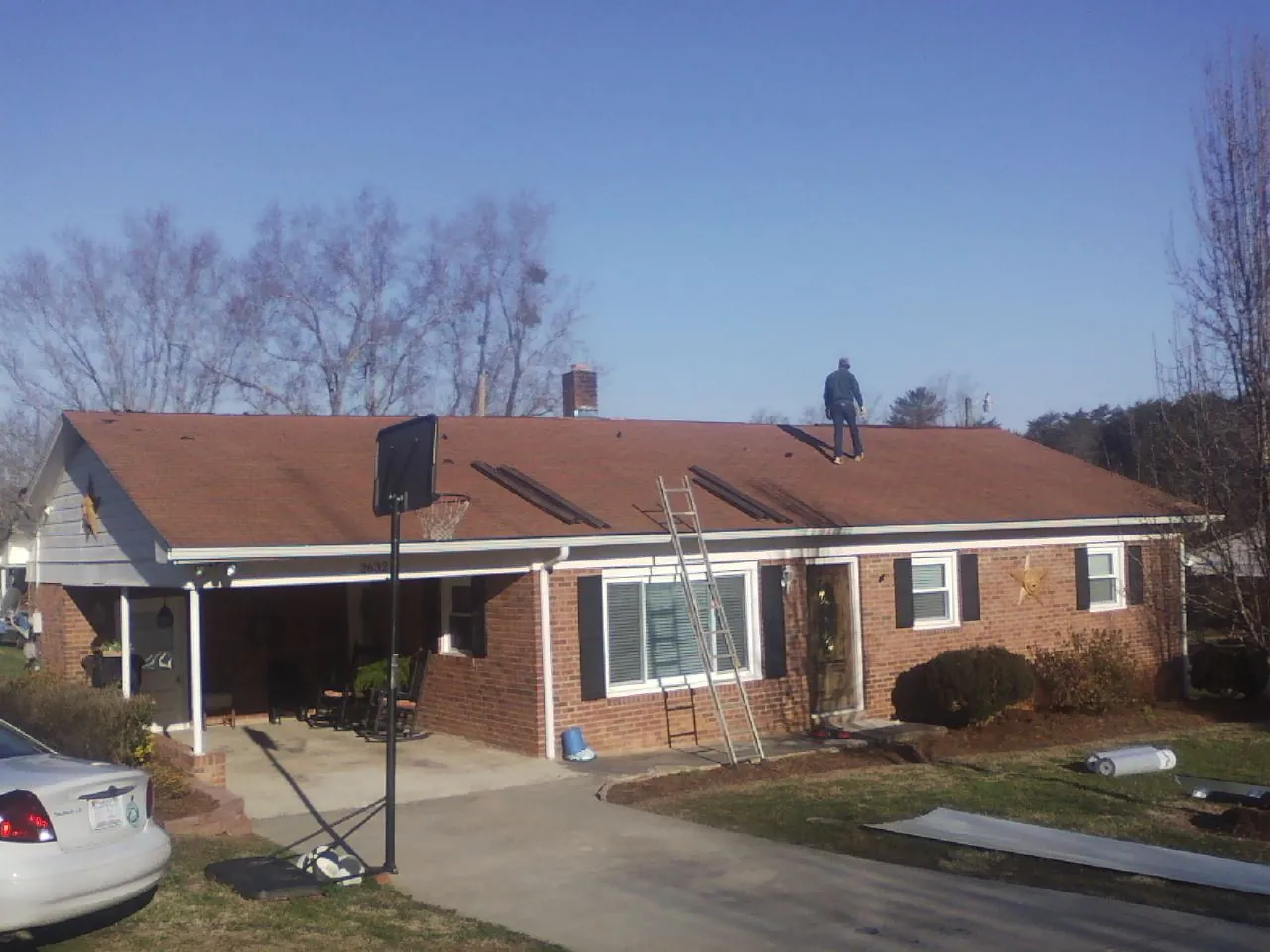 Roofer stripping a shingle roof on a brick ranch before metal panels in North Street