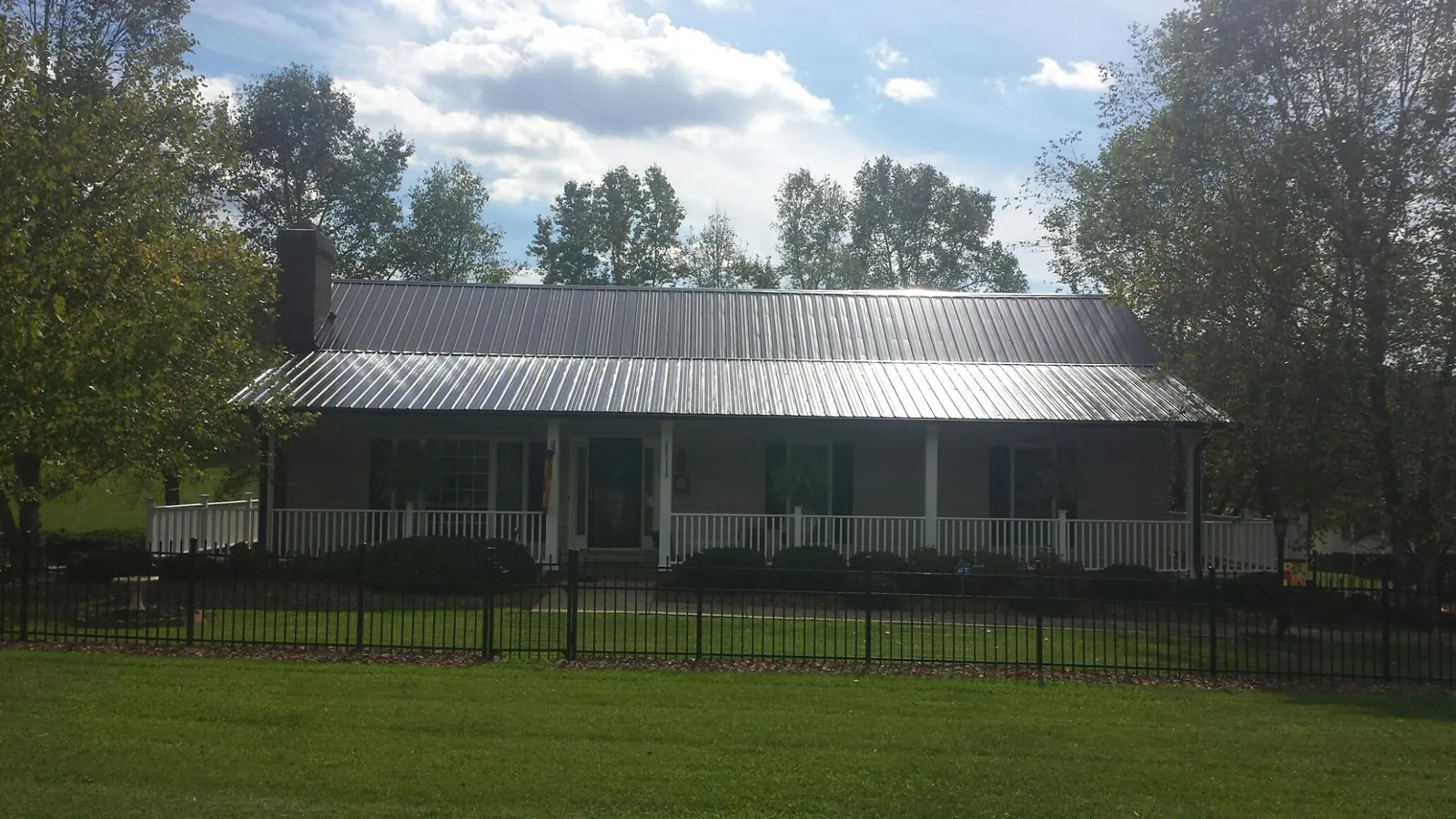 Gray metal roof on a brick ranch with a full width front porch — Gutter Guard Installation work by our crew in North Street