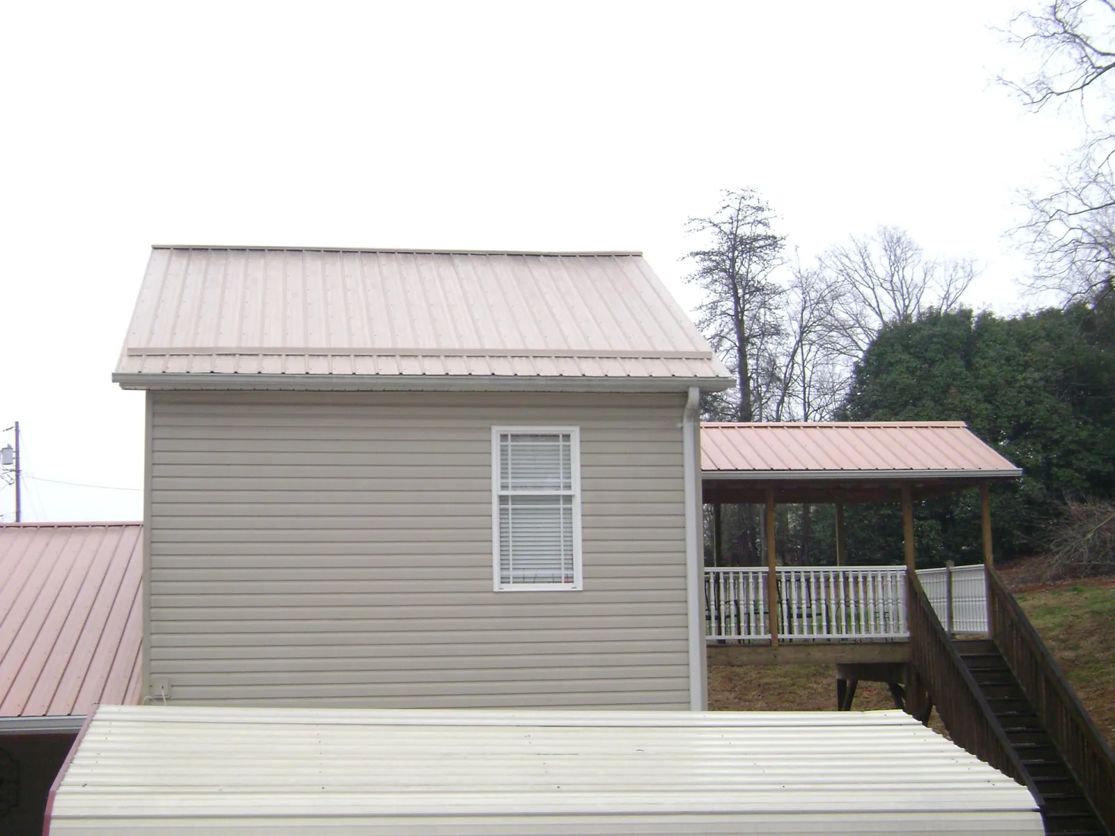 Tan metal roofs on a two story addition and attached porch, from a Roof Replacement job in North Street